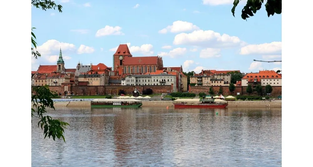 Foto Kota Torun yang menjadi kota kelahiran Copernicus ketika hari sedang cerah dan beberapa perahu terlihat sedang melewati sungai.